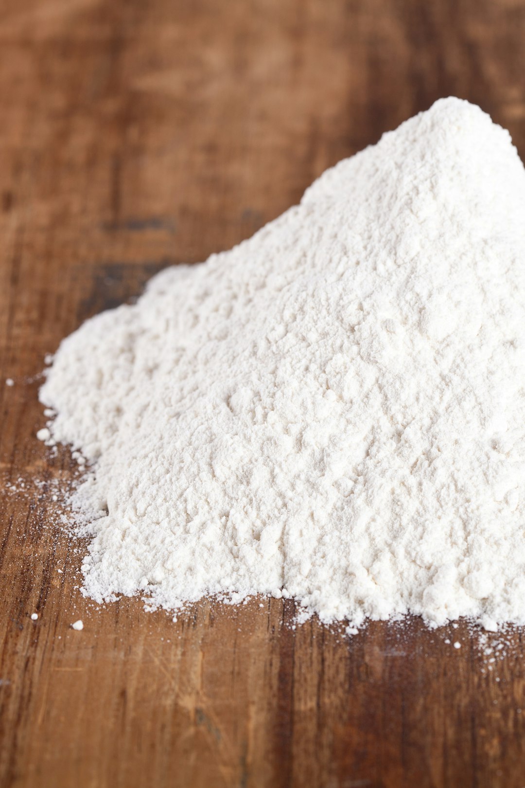 Pile of white crystalline powder on a wooden table