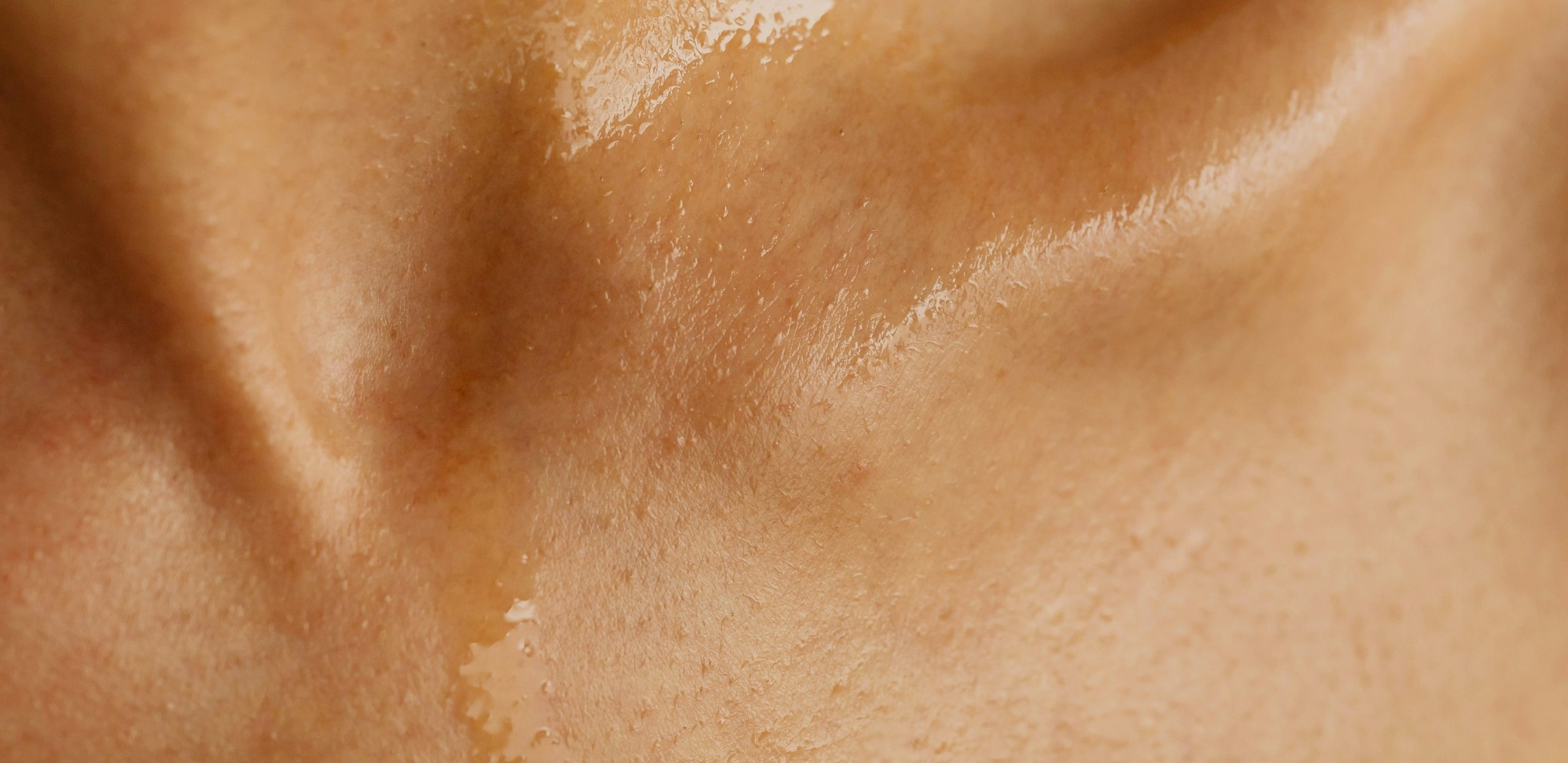 Close-up of glistening, wet human skin, showing texture, pores, and subtle shadows. The lighting highlights the smoothness and moisture on the skin’s surface after cleansing with Goodlather bar soap.