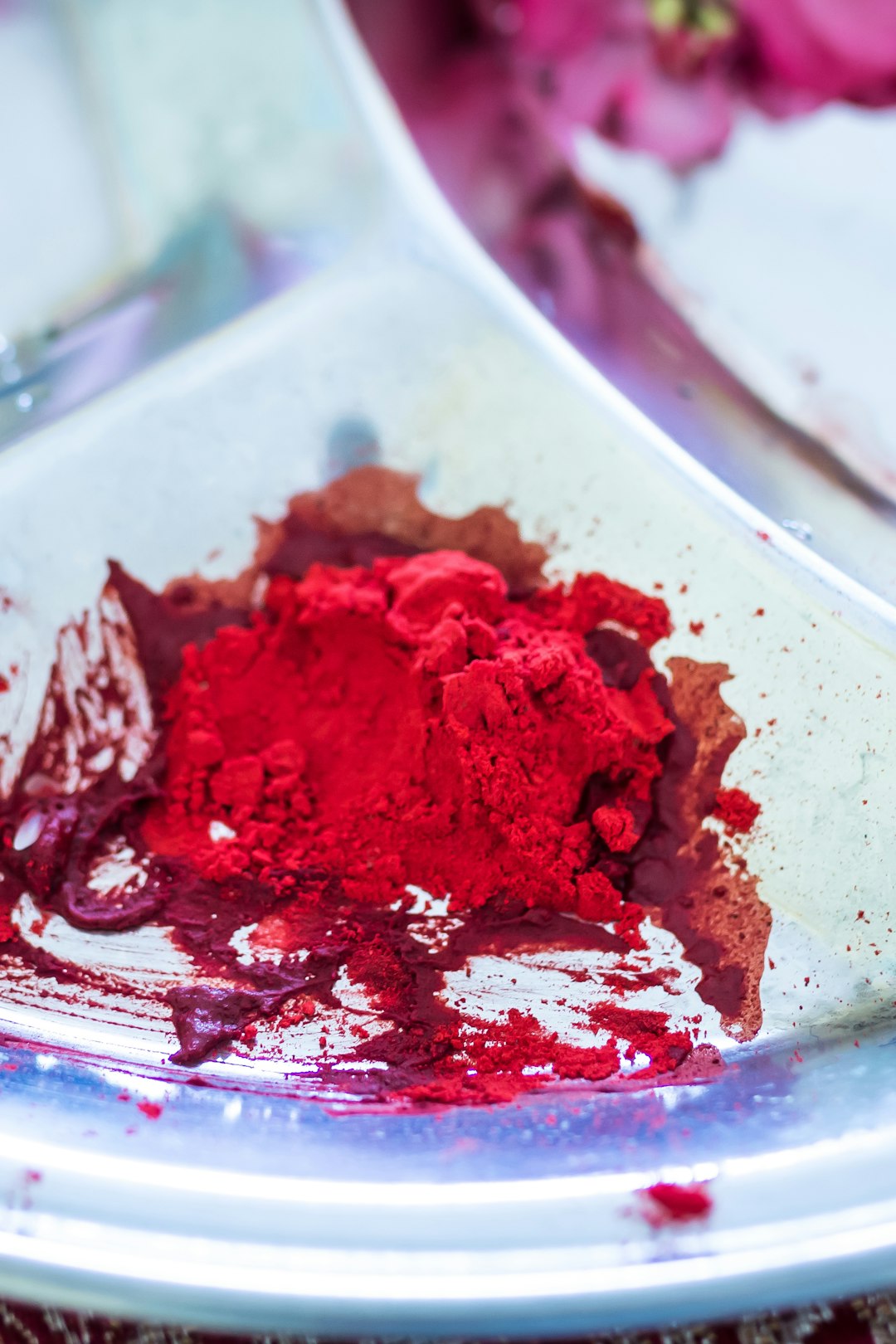 Red natural pigment powder on a white ceramic plate